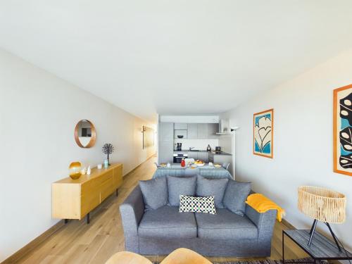 un salon avec un canapé bleu et une cuisine dans l'établissement -PAOLO- Beau T2 avec Vue Mer et Parking, à Concarneau
