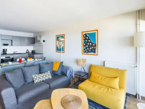sala de estar con sofá azul y silla amarilla en -PAOLO- Beau T2 avec Vue Mer et Parking, en Concarneau