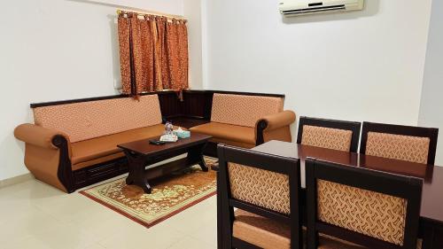 a living room with a couch and a table and chairs at Dahlia Sohar Hotel Apartments in Sohar