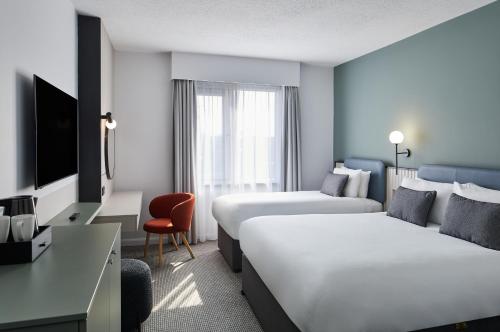 a hotel room with two beds and a desk at Leonardo Hotel Dublin Parnell Street in Dublin