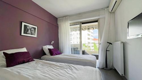 Ce lit se trouve dans un dortoir doté de murs violets et d'une fenêtre. dans l'établissement 2 Room modern, terrace and Parking, à Cannes