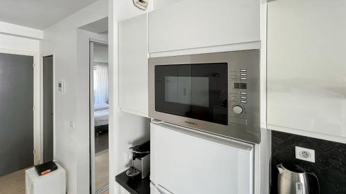 une cuisine avec un four micro-ondes dans un mur blanc dans l'établissement 2 Room modern, terrace and Parking, à Cannes