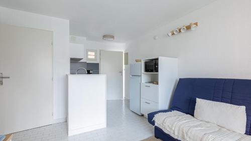 - un salon avec un canapé bleu et un réfrigérateur dans l'établissement SANTA MONICA II -112- Appt 4-6 pers avec veranda, au Cap d'Agde