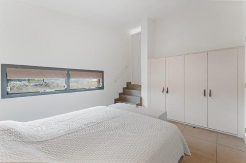a white bedroom with a bed and a window at Beachfront VIP Villa - 4p - Luxe & Strand op 50m - Villa 59 in Ouddorp