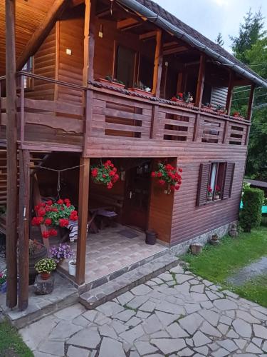 a large wooden house with flowers in front of it at Casa ,,Kiss-lak,, in Praid