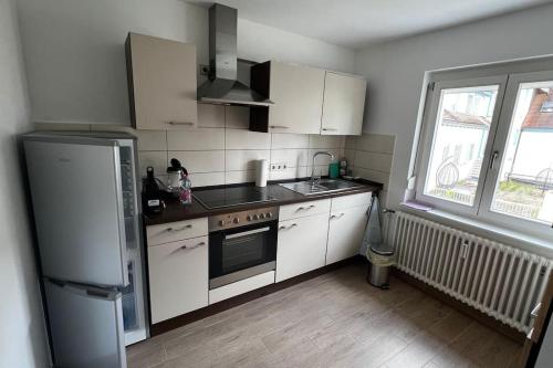 a kitchen with white cabinets and a refrigerator at Wohnung direkt am See, 58 qm in Reichenau