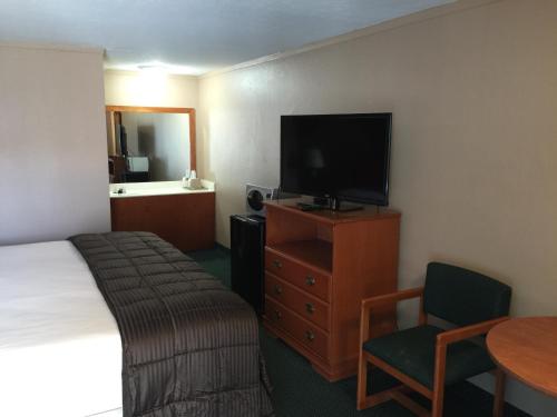 um quarto de hotel com uma cama, uma televisão e uma mesa em Budget Inn - Saint Robert em Saint Robert