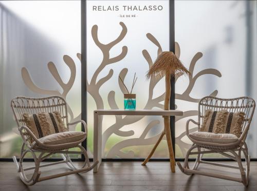two chairs and a table in front of a wall at Hôtel Atalante - Relais Thalasso & Spa in Sainte-Marie-de-Ré
