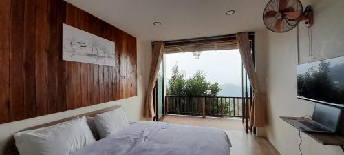 a bedroom with a bed and a large window at KHIRI HOUSE &Café Farm ดอยช้างเชียงรายที่พักอาข่าเรียวกังสไตล์กลางหมู่บ้านดอยช้าง in Ban Rong Than