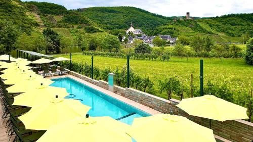 a row of yellow umbrellas next to a swimming pool at Mosel Village Resort in Ellenz-Poltersdorf