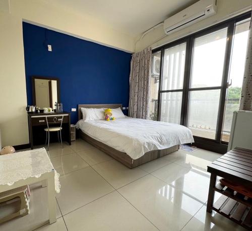 a bedroom with a blue wall and a bed and a desk at 羅東夜市長虹 in Luodong