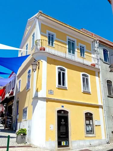 a yellow and white building with a balcony at The Corner House - Charming Rustic Home in the Heart of Monchique in Monchique