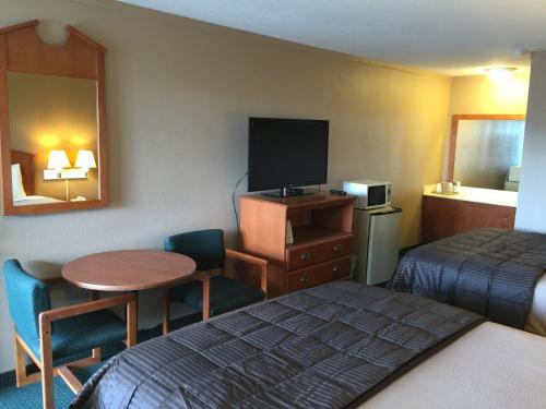 a hotel room with a bed and a table and a tv at Budget Inn - Saint Robert in Saint Robert