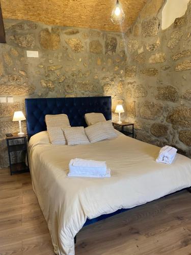 a bedroom with a large bed in a stone wall at Casa de Pedra em Vinha no Dão in Nelas