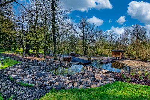 a pond in a garden with rocks and trees at Cardoner Hotel és Konferenciaközpont in Dobogoko