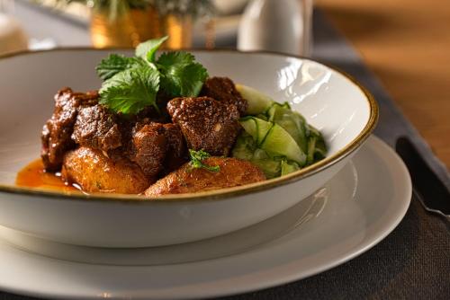 a bowl of food on a plate on a table at Cardoner Hotel és Konferenciaközpont in Dobogoko