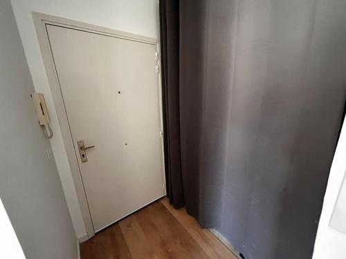 un couloir vide avec une porte blanche et du parquet dans l'établissement Superbe studio climatisé avec terrasse proche mer, à Cagnes-sur-Mer