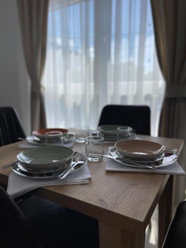 a wooden table with plates and silverware on it at Relax Apartmani in Sutomore