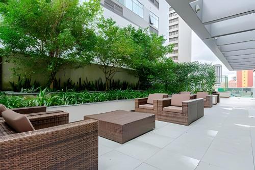 a patio with chairs and tables in a building at 7th Avenue - Apartamentos UROOMS in Curitiba