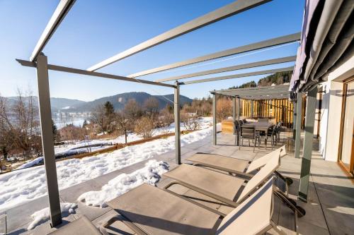 a covered deck with a table and chairs in the snow at Moho Mountain Home in Gérardmer