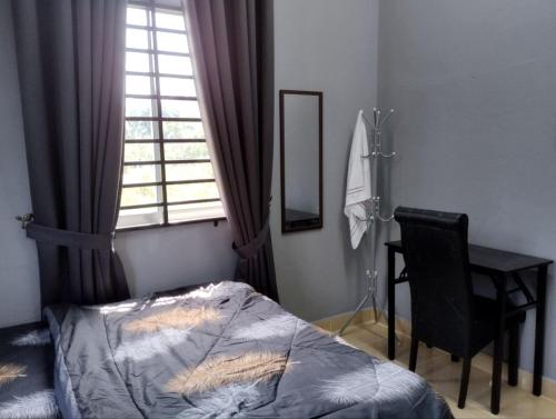 a bedroom with a bed and a desk and a window at SH Homestay in Kota Bharu