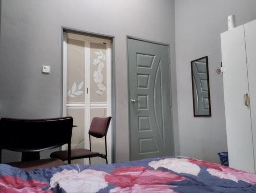 a bedroom with a bed and a door and a chair at SH Homestay in Kota Bharu