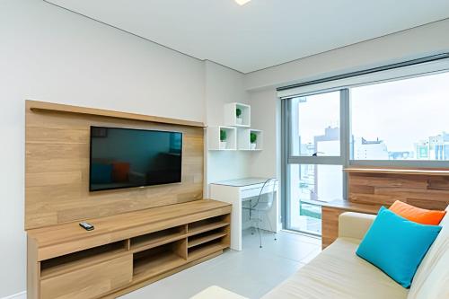 a living room with a television and a couch at 7th Avenue - Apartamentos UROOMS in Curitiba