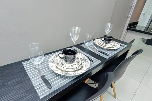 a table with two glasses and a plate with two cups at 7th Avenue - Apartamentos UROOMS in Curitiba