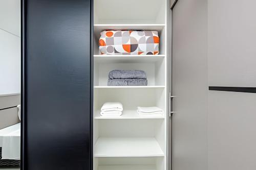a closet with a black door and white shelves at 7th Avenue - Apartamentos UROOMS in Curitiba