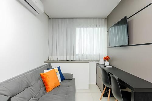 a living room with a gray couch and a desk at 7th Avenue - Apartamentos UROOMS in Curitiba