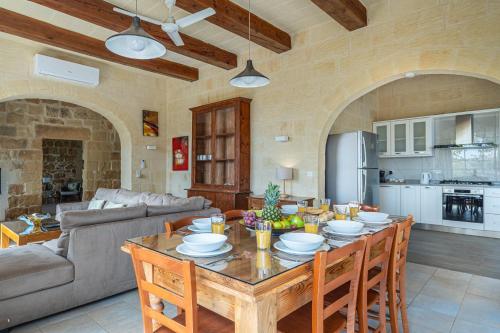 a living room with a table with chairs and a kitchen at Sinjura Holiday Home in Xagħra