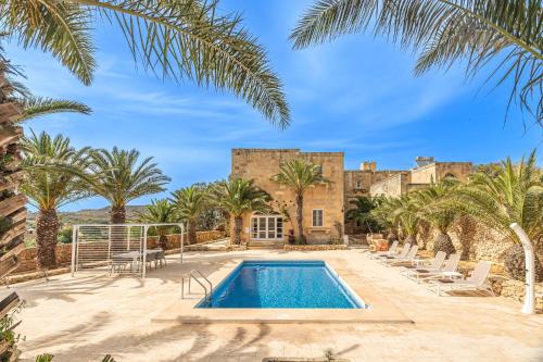a villa with a swimming pool and palm trees at Sinjura Holiday Home in Xagħra