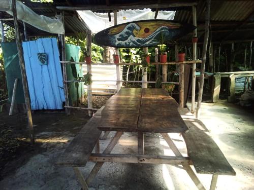 a wooden picnic table in a building with a surfboard at Miguel Surf Camp in Quepos