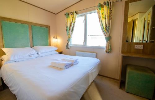 a bedroom with a white bed with towels on it at SBL48 Camber Sands Holiday Park in Camber