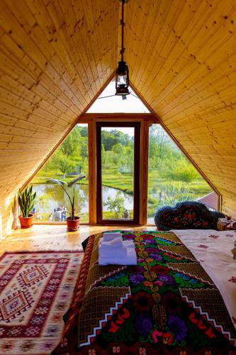 a room with a large bed with a large window at Cabană tip A Wild Glamping Cornereva in Cornereva