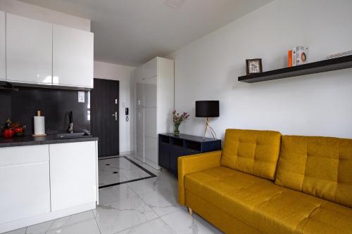 a living room with a yellow couch and a kitchen at MOVEEN! Wynajem apartamentów we Wrocławiu! 10 minut od centrum in Wrocław