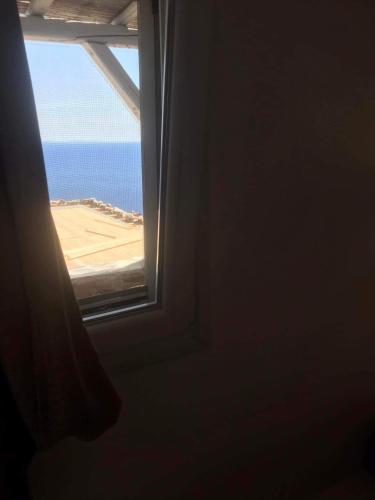 an open window with a view of the beach at Darsi suites Kythnos in Kithnos
