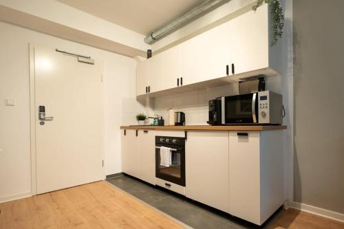 eine Küche mit weißen Schränken und einer Mikrowelle in der Unterkunft Hamburg City Apartment for 4 in Hamburg