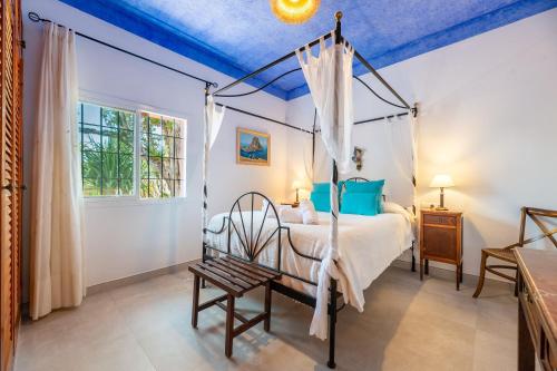 a bedroom with a canopy bed and a chair at Villa Can Cardona in Montecristo
