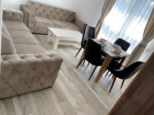 a living room with a couch and a table and chairs at Relax Apartmani in Sutomore