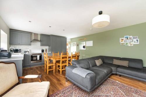 un soggiorno con un divano nero e una cucina di Delightful Garden Upper Cottage in Oldhamstocks East Lothian a Oldhamstocks