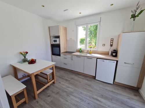 une cuisine avec des armoires blanches, une table et un évier dans l'établissement Dépendance avec place de parking, à Sainte-Soulle