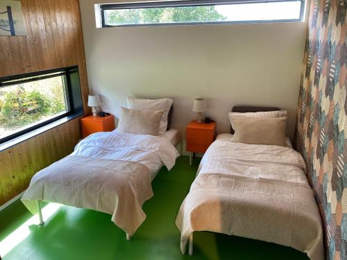 two beds in a room with two windows at 't UijlenHuijs in Dussen