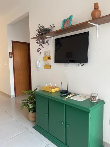 a green cabinet with a flat screen tv on a wall at Vila Girassol in Aracaju