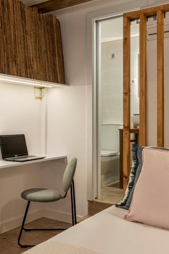 a bedroom with a bed and a chair and a laptop at Chalet Marias - Parede beach apartments in Parede