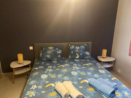 - une chambre avec un lit avec une couette bleue et 2 tables dans l'établissement Rez de villa Grand T2 proche plage Marvivo-Sablettes, à La Seyne-sur-Mer