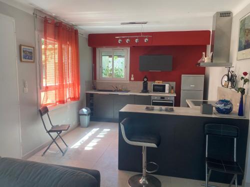 une cuisine avec des murs rouges et un îlot bleu dans une pièce dans l'établissement Rez de villa Grand T2 proche plage Marvivo-Sablettes, à La Seyne-sur-Mer