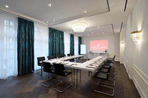 a meeting room with a long table and chairs at Kastens Hotel Luisenhof in Hannover