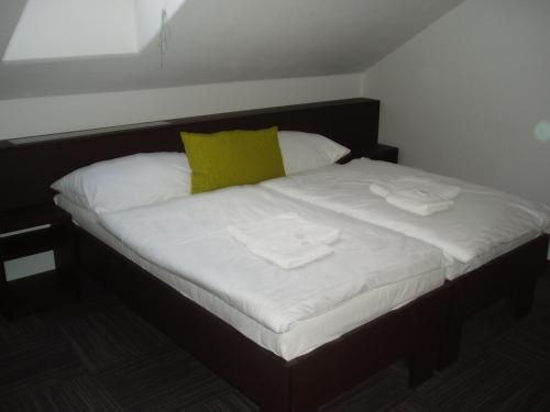 a bed with white sheets and two towels on it at Hotel Kaskada in Ledeč nad Sázavou