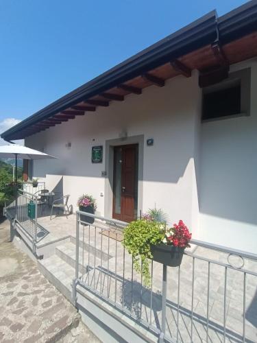 a white house with potted plants on the balcony at Monte Zucco Relax self check in in San Pellegrino Terme